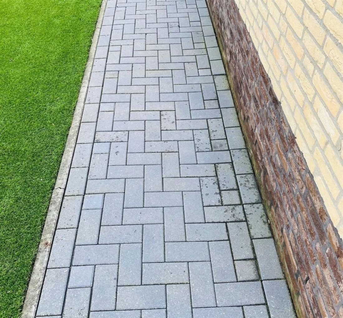 Schoon grijs visgraat-tegelpad langs de gevel